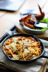 Cheesy spaghetti bolognese serve on pan metal top wood tray with fork and spoon side have chicken...