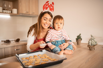 A mother baking cookies with her baby.