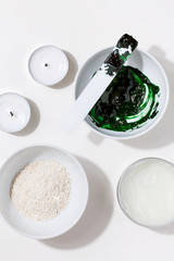Spa cosmetics and body skin care treatment creative top view flat lay concept.Preparing natural cosmetic green spirulina cleansing mask bowl on white background.Homemade beauty product