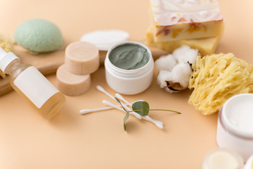 Fototapeta na wymiar beauty, spa and wellness concept - close up of crafted soap bars, natural bristle wooden brush, body butter with sponge and herbs on beige background