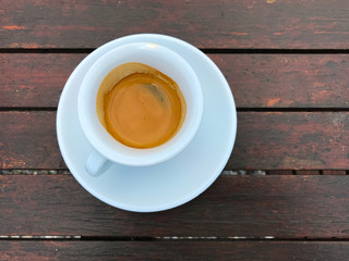 Espresso coffee in a white cup and saucer on a wooden table