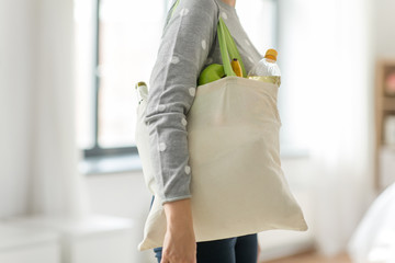 consumerism, eating and eco friendly concept - woman with white reusable canvas bag for food...