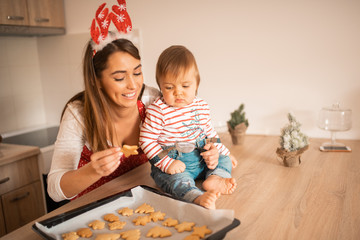 A mother and a child baking cookies for Christmas in the kitchen.