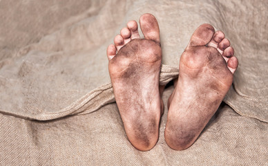 Poor man's feet. The person is lying on a simple homespun cloth. (сoncept of poverty, death)