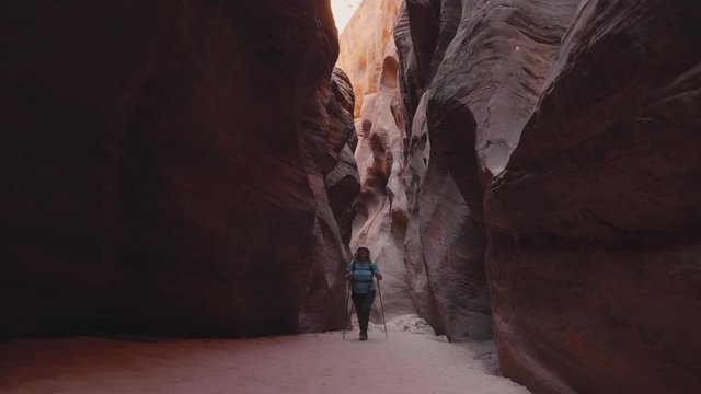 Tourist Hiking On Dry Riverbed In Deep Slot Canyon With Orange Smooth Rocks