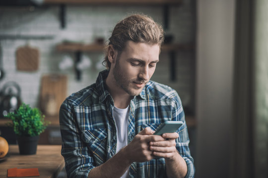 Handsome young man texting with his girlfriend using a smartphone