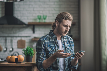 Young man holding a smartphone feeling disappointed with the message