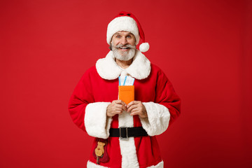 Joyful elderly gray-haired mustache bearded Santa man in Christmas hat posing isolated on red background. Happy New Year 2020 celebration holiday concept. Mock up copy space. Holding passport ticket.