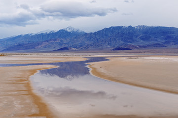 Landscape of the salt flats of Cottonball Basin with reflections in calm water, Death Valley National Park, California, USA