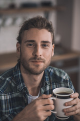 Handsome long-haired man drinking his morning coffee
