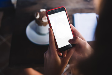 Woman using smartphone while sitting with dessert in cafe