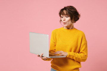 Amazed young brunette woman girl in yellow sweater posing isolated on pastel pink background studio...
