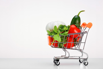 Side view of a shopping cart full of fresh vegetables and  groceries