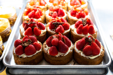 On the window are desserts with strawberries. Sponge cake with meringue. Filling. Showcase with pastries in the store. Sweets in the fridge for the holiday. Cakes and pastries for every taste. - Powered by Adobe