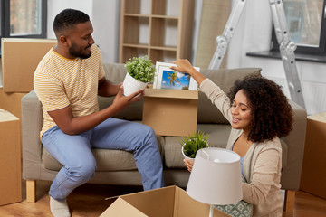 moving, people, repair and real estate concept - happy african american couple with photo frame and...