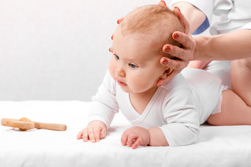 Little baby receiving osteopathic treatment of head and neck - obrazy, fototapety, plakaty