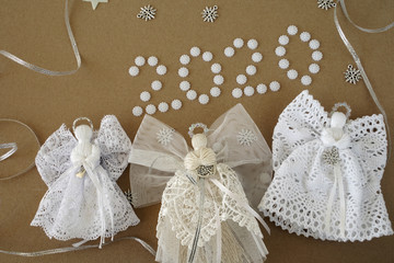 Christmas 2020 decorations on paper background. angel, text "2020", lace and pearls