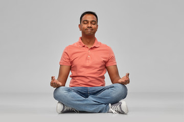 meditation, mindfulness and people concept - happy indian mant meditating in lotus yoga pose over...