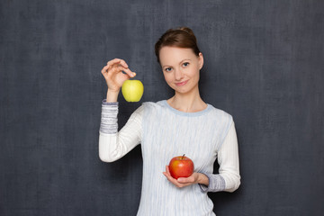 Portrait of happy young woman smiling and holding two ripe apples