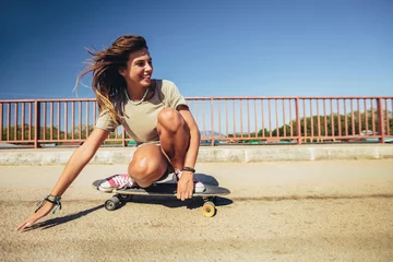 Poster Im Rahmen Young sporty woman riding on the skateboard on the road. © Mediteraneo