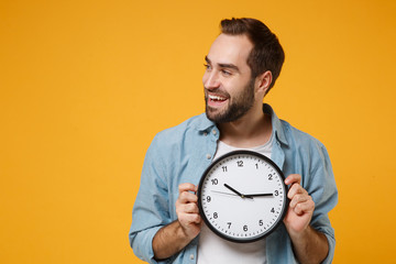 Handsome young man in casual blue shirt posing isolated on yellow orange background, studio...