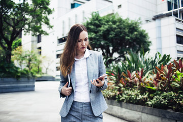 Pensive woman in suit using phone