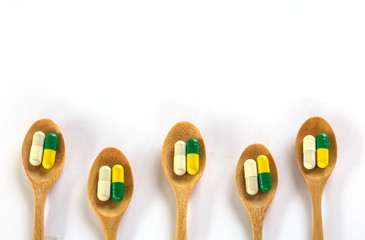 Colorful of capsule pills in wooden spoon  on white background.