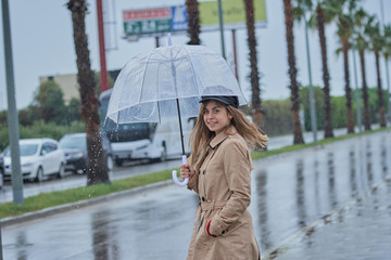 A girl with a transparent umbrella waiting to cross the street, it's raining