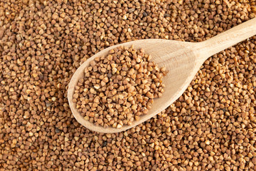 glass jar with buckwheat and a wooden spoon on white isolate background