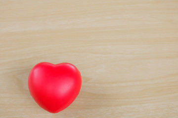 Red heart on hand on wooden background.