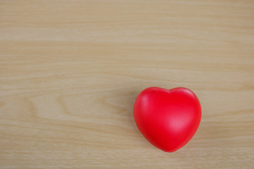 Red heart on hand on wooden background.