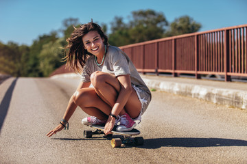 Young sporty woman riding on the skateboard on the road. - Powered by Adobe