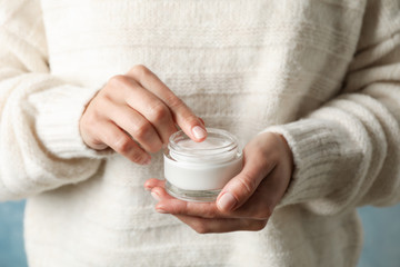 Woman holding jar of moisturizing cream, closeup. Winter cosmetic. Space for text
