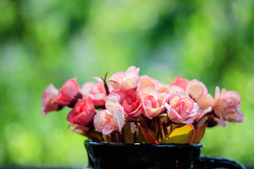 Vase with artificial flowers on a natural background.