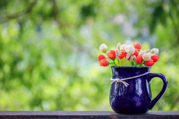 Vase with artificial flowers on a natural background.