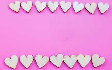 Many small wooden hearts on a pink background and copy space.