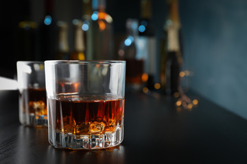 Glasses of whiskey on bar counter, close up and space for text