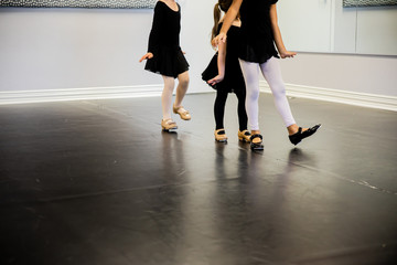 Girls lined up in tap shoes on dance class floor