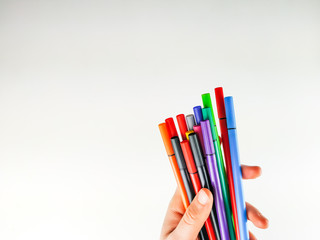 Female white hand holding multiple colorful pens with caps on white background for expressing creativity on blank canvas and good for studying and business organization