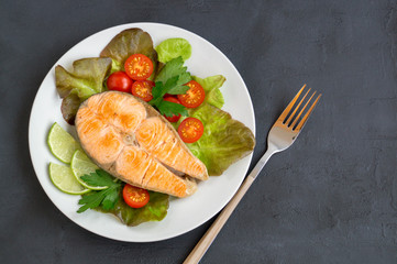 grilled salmon steak with vegetables. on a dark table.
