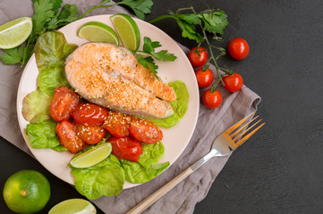grilled salmon steak with vegetables. on a dark table.
