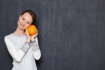 Portrait of happy girl smiling and holding ripe grapefruit in hands