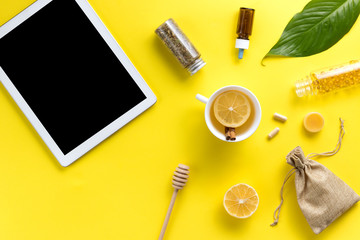 Illness concept. Composition alternative medicine. Herbal tea, ginger, lemon and gadget on a yellow background. Flat lay. View from above. Copy space