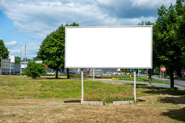 Blank white billboard for advertisement in the city. Sumeer day, blue sky with some white clouds.