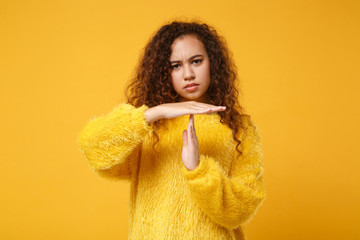 Concerned young african american girl in fur sweater posing isolated on yellow background. People...