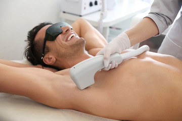 Young man undergoing laser epilation procedure in beauty salon