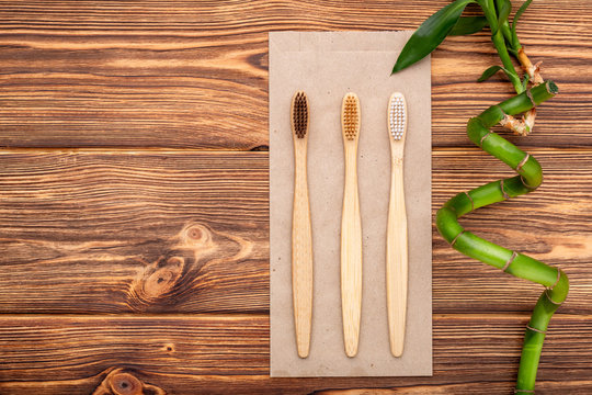 Bamboo toothbrushes, bamboo branch on wooden background. Flat lay copy space. Natural bath products. Biodegradable natural bamboo toothbrush. Eco friendly, Zero waste, Dental care Plastic free concept