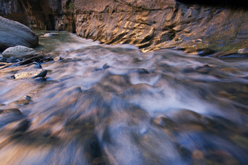Landscape of the Virgin River Narrows captured with motion blur and illuminated by reflected color from sunlit canyon cliffs, Zion National Park, Utah, USA