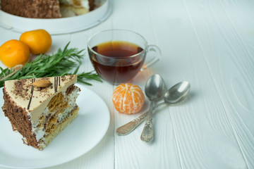 Cake with almonds and poppy seeds, cream on a white plate on the table on a light wooden background. Tea party with cake. Dining table. Space for text.