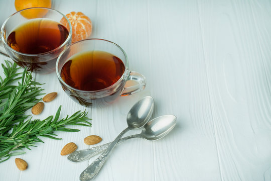 Tea in a glass cup on a light wooden background. Black tea with rosemary, tangerines. Space for text. Background menu table.